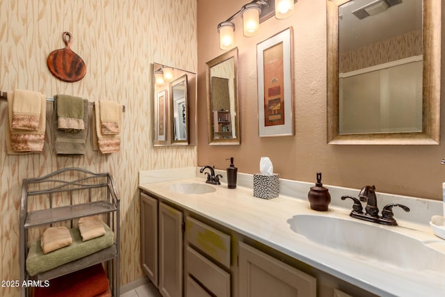 bathroom with double vanity, visible vents, wallpapered walls, and a sink