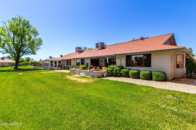 back of house featuring a patio area, central AC unit, a yard, and a shingled roof
