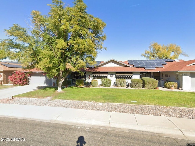 ranch-style home featuring solar panels, a front yard, and concrete driveway
