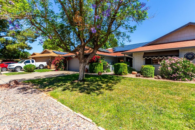 ranch-style home with brick siding, a garage, solar panels, driveway, and a front lawn