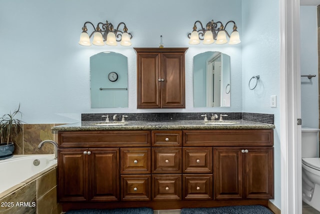 bathroom featuring vanity, tiled tub, and toilet