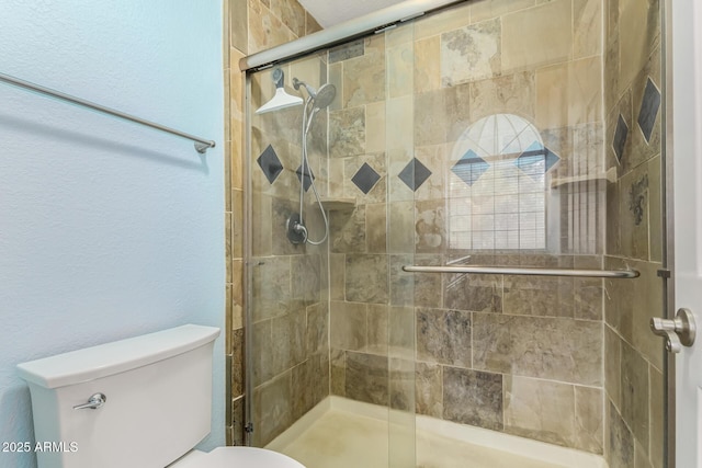 bathroom featuring a shower with door and toilet