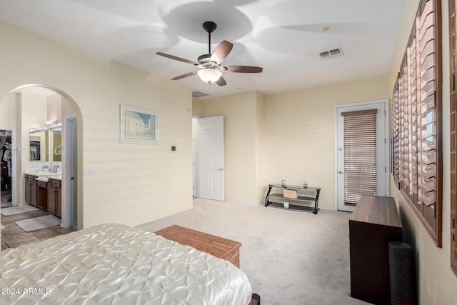 bedroom featuring connected bathroom, ceiling fan, a closet, and light colored carpet