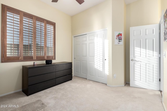 carpeted bedroom with ceiling fan, multiple windows, and a closet