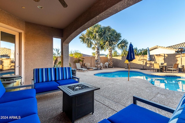 view of swimming pool with ceiling fan, a patio area, and an outdoor living space with a fire pit