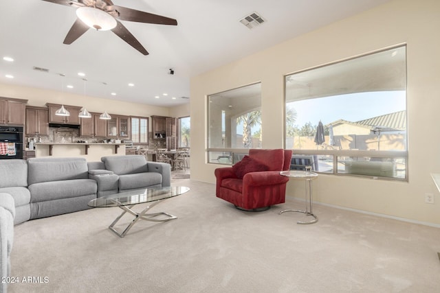 living room with a wealth of natural light, ceiling fan, and light carpet