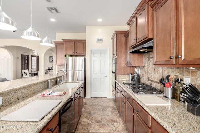 kitchen featuring light stone countertops, tasteful backsplash, stainless steel appliances, sink, and decorative light fixtures