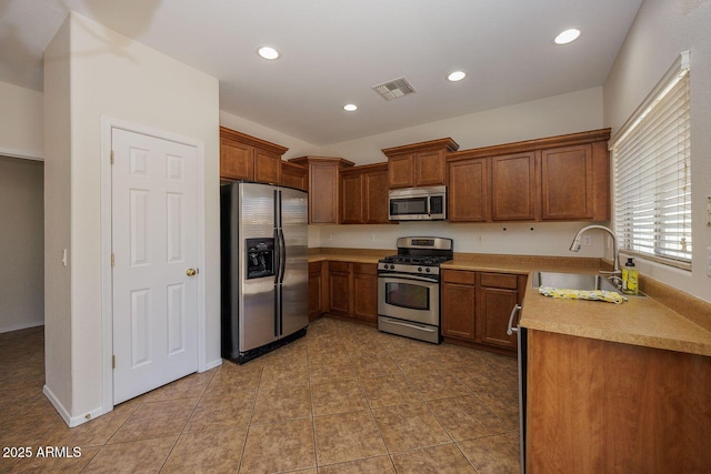 kitchen featuring brown cabinetry, visible vents, a sink, light countertops, and stainless steel appliances