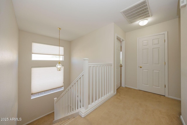 hall featuring visible vents, carpet flooring, baseboards, and an upstairs landing