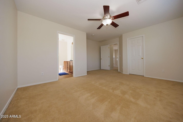 unfurnished bedroom with baseboards, ensuite bathroom, light carpet, and a ceiling fan