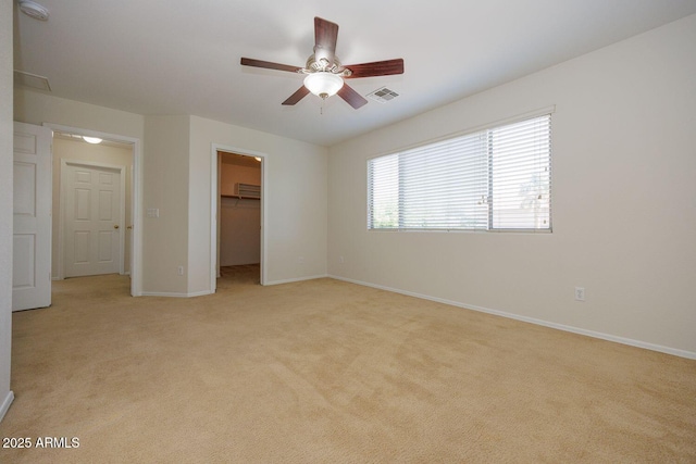 unfurnished bedroom with baseboards, visible vents, light carpet, and a walk in closet
