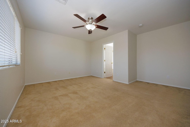 empty room with baseboards, ceiling fan, and light colored carpet