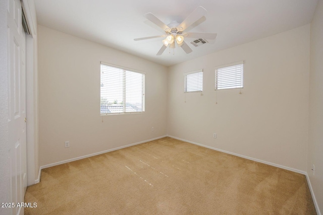 unfurnished room with light colored carpet, baseboards, visible vents, and a ceiling fan