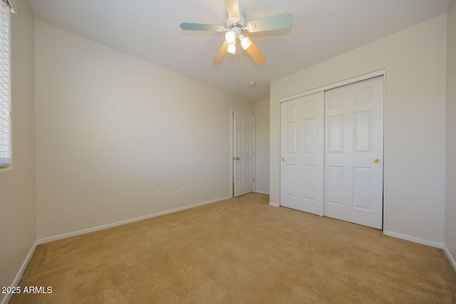 unfurnished bedroom featuring baseboards, ceiling fan, light carpet, and a closet