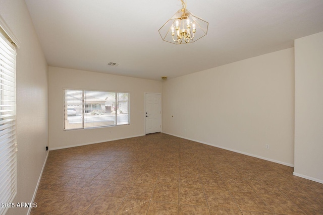 unfurnished room featuring baseboards, a chandelier, and visible vents