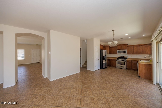 kitchen featuring appliances with stainless steel finishes, a sink, light countertops, arched walkways, and recessed lighting