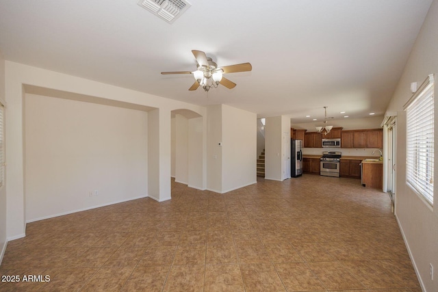 unfurnished living room with visible vents, stairs, baseboards, ceiling fan, and a sink