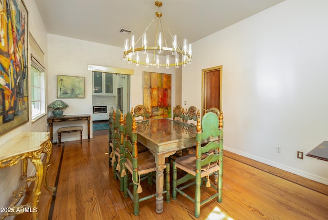 dining area with hardwood / wood-style flooring and a notable chandelier