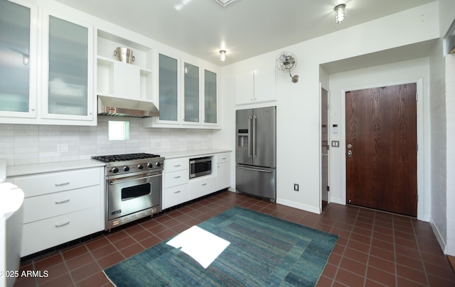 kitchen featuring high end appliances, white cabinetry, tasteful backsplash, and dark tile patterned floors