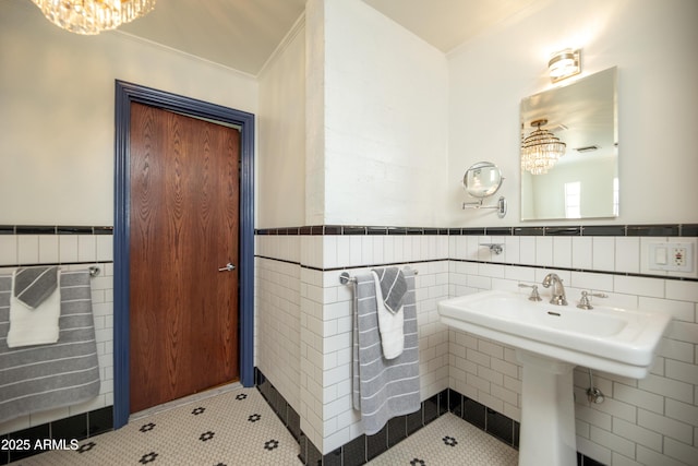 bathroom featuring an inviting chandelier, ornamental molding, and tile walls