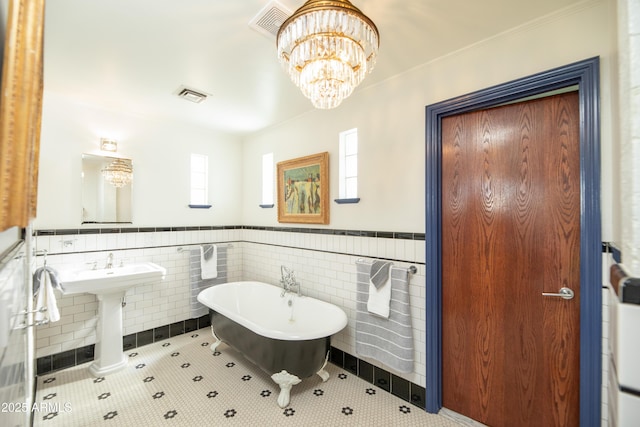 bathroom with a tub, tile walls, a chandelier, crown molding, and tile patterned floors