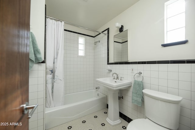 bathroom with tile patterned flooring, shower / bath combo, tile walls, and toilet