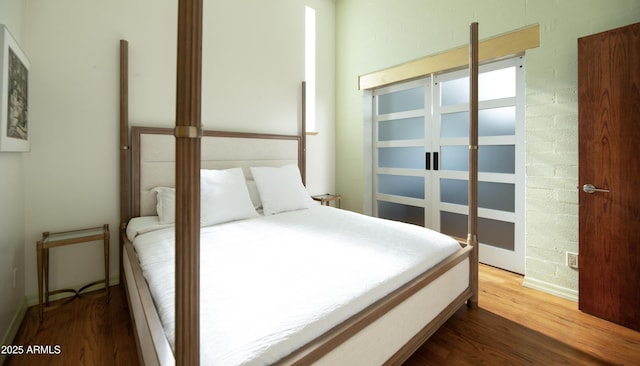 bedroom featuring brick wall and dark hardwood / wood-style floors