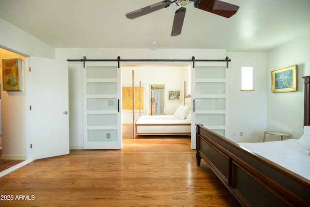 bedroom with a barn door and light wood-type flooring