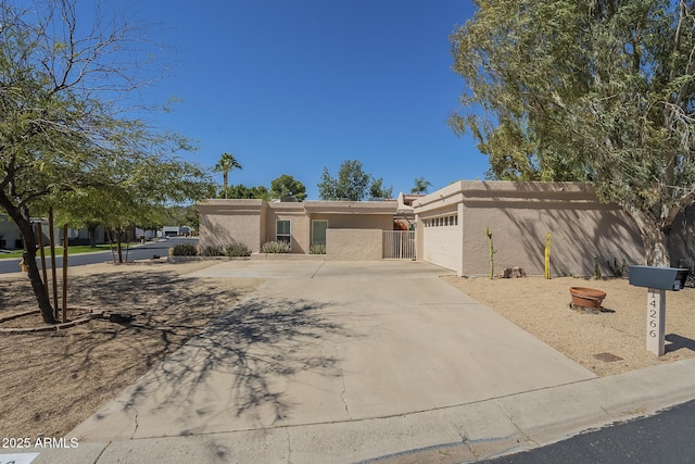 view of front of home featuring stucco siding, an attached garage, concrete driveway, and fence