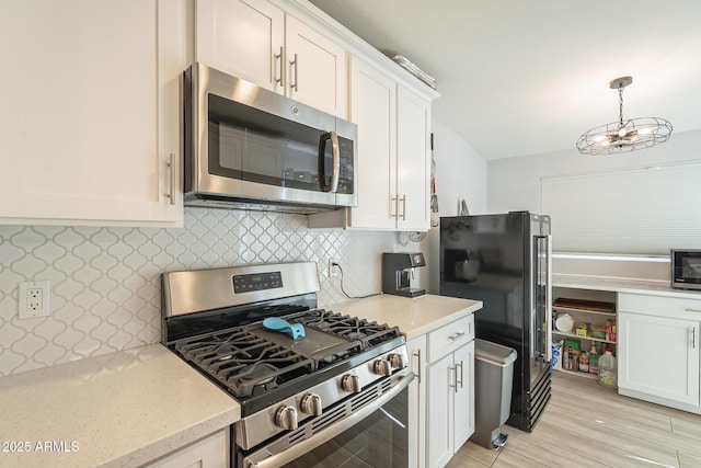 kitchen with light stone counters, stainless steel appliances, tasteful backsplash, and white cabinets