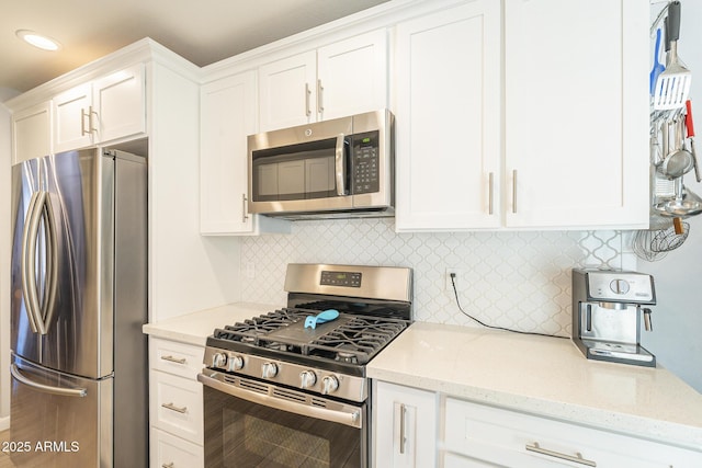 kitchen with light stone counters, backsplash, recessed lighting, stainless steel appliances, and white cabinets