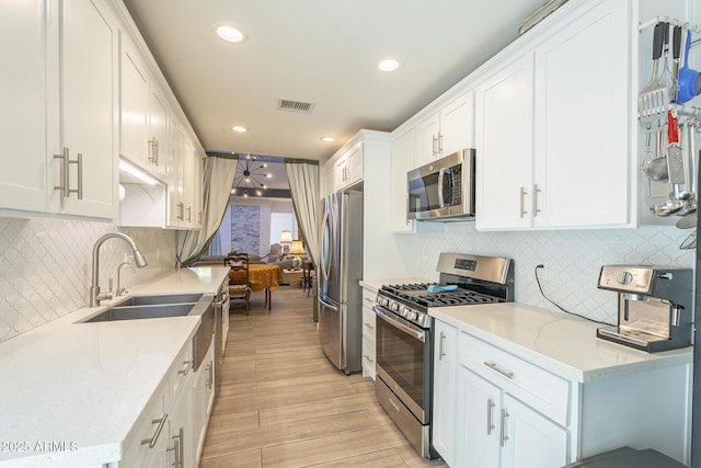 kitchen featuring visible vents, appliances with stainless steel finishes, light wood-style floors, white cabinets, and a sink