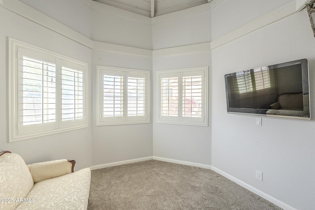 living area featuring carpet flooring, a high ceiling, and baseboards