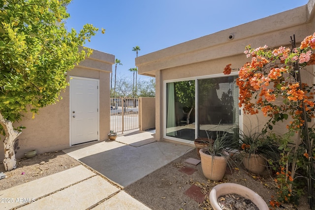 property entrance featuring a patio, a gate, and stucco siding