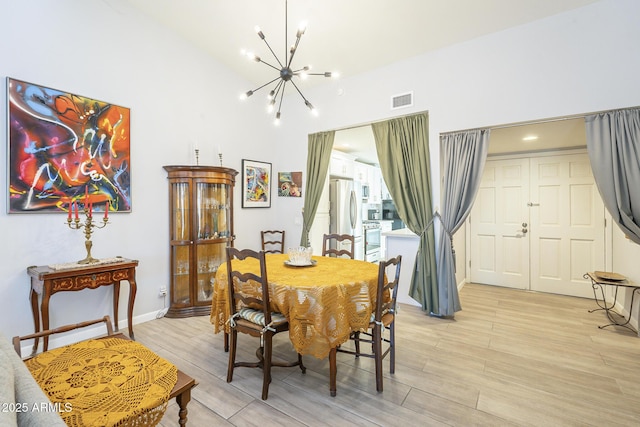 dining room with light wood finished floors, visible vents, lofted ceiling, and a notable chandelier