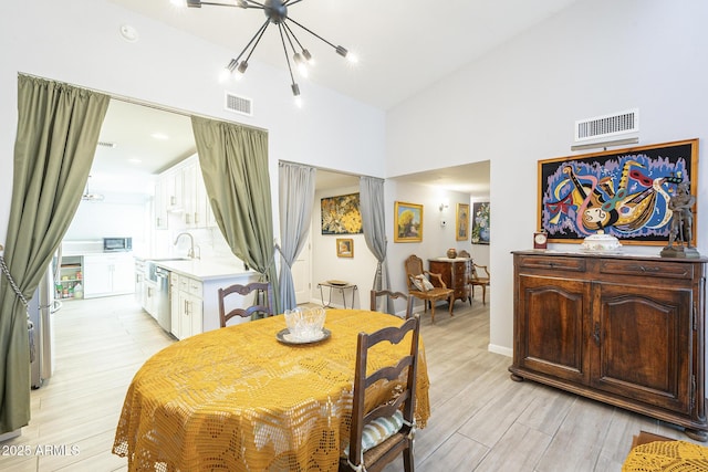 dining area with visible vents, high vaulted ceiling, and light wood finished floors