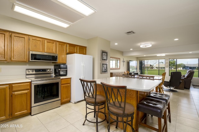 kitchen featuring stainless steel appliances, a kitchen bar, a kitchen island, and plenty of natural light