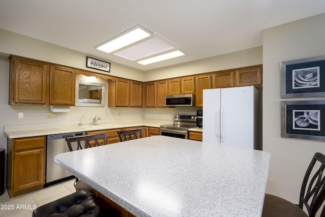 kitchen featuring sink, a kitchen breakfast bar, a center island, light tile patterned floors, and stainless steel appliances