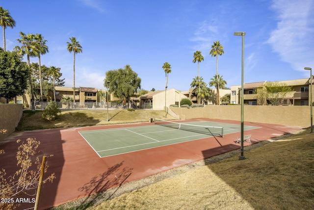 view of tennis court with a yard and basketball hoop