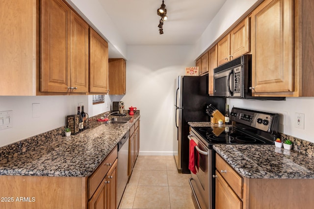 kitchen with light tile patterned floors, track lighting, dark stone countertops, and stainless steel appliances