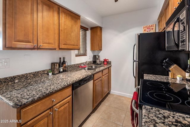 kitchen with light tile patterned floors, sink, dark stone countertops, and stainless steel appliances