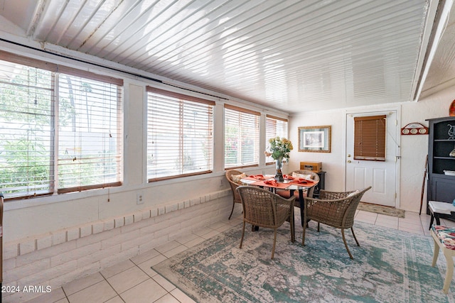 tiled dining room with plenty of natural light and brick wall