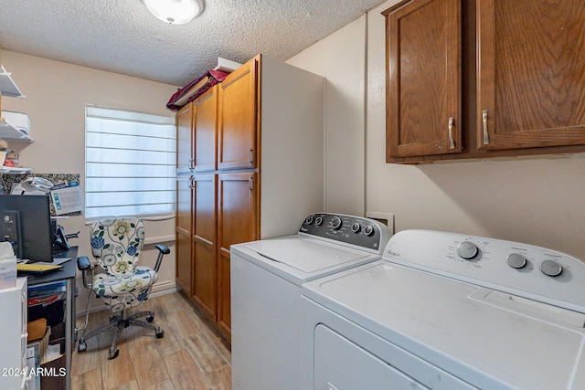 laundry area featuring washing machine and clothes dryer, cabinets, a textured ceiling, and light wood-type flooring