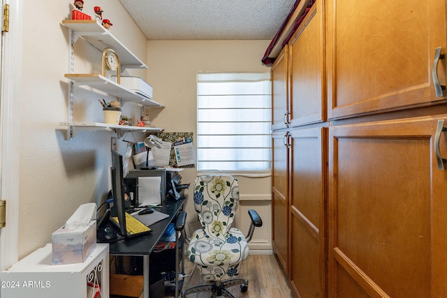 home office with light hardwood / wood-style floors and a textured ceiling