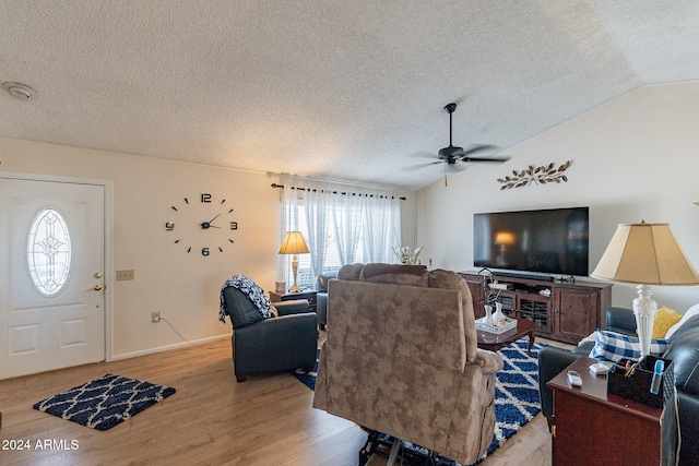 living room with a textured ceiling, ceiling fan, light hardwood / wood-style flooring, and vaulted ceiling