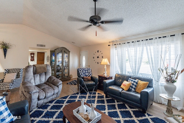 living room with a textured ceiling, hardwood / wood-style flooring, vaulted ceiling, and ceiling fan