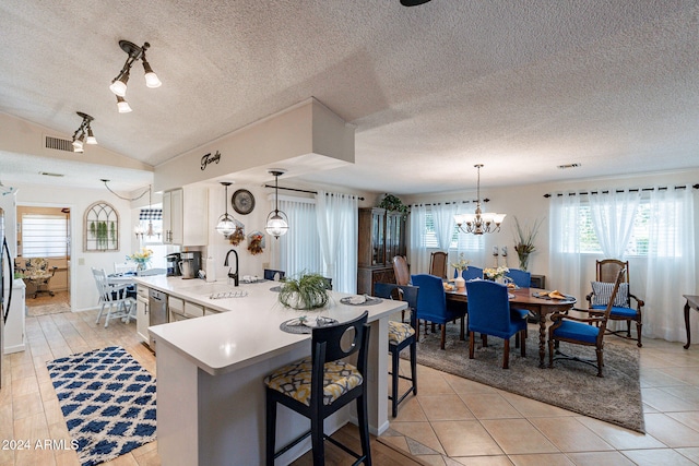 kitchen with a textured ceiling, white cabinetry, light tile patterned floors, and decorative light fixtures