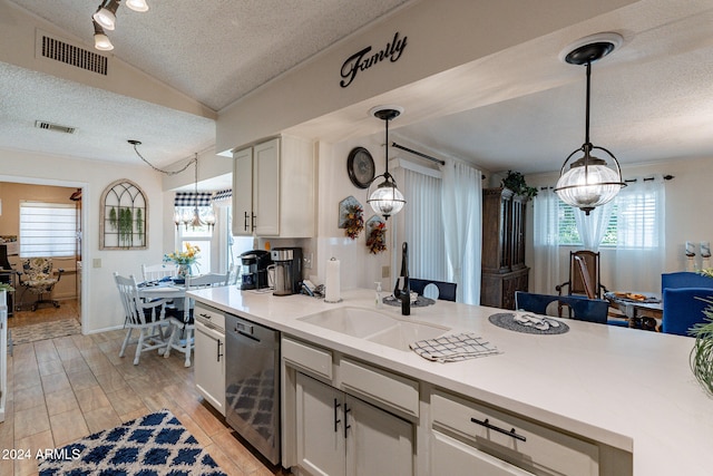 kitchen with stainless steel dishwasher, a textured ceiling, lofted ceiling, white cabinets, and light wood-type flooring