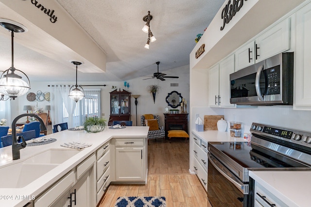 kitchen with appliances with stainless steel finishes, a textured ceiling, sink, white cabinets, and light hardwood / wood-style floors