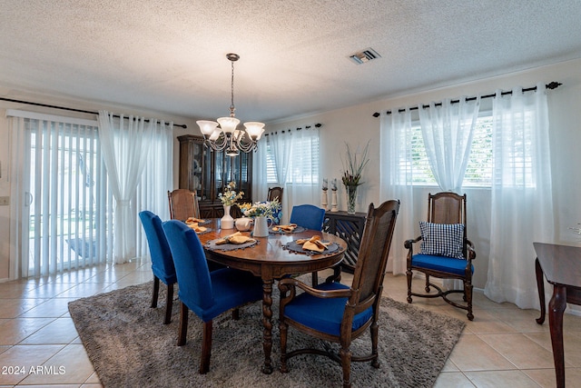 dining area with light tile patterned floors, a textured ceiling, and an inviting chandelier